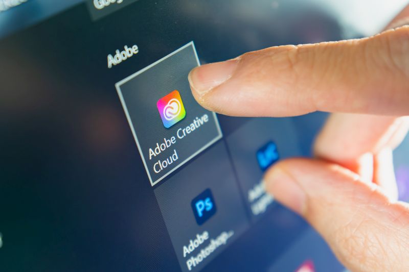 BangkokComputer user touching on Adobe Creative Cloud icon to open the software.